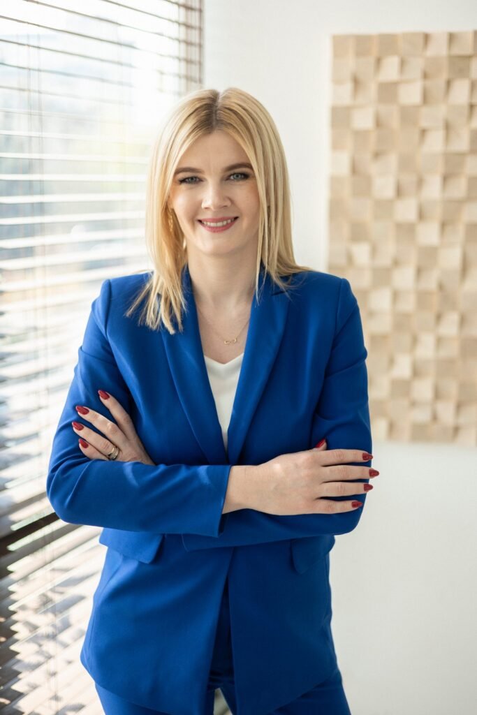 Małgorzata Jaszczyk w kobaltowym garniturze z rękami skrzyżowanymi na piersi