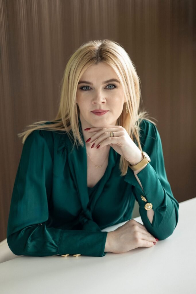 Małgorzata Jaszczyk w zielonej bluzce przy biurku